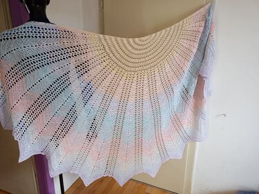 Halbrundes gehäkeltes Tuch in Pastellfarben mit filigranem Spitzenmuster auf einer Schaufensterpuppe