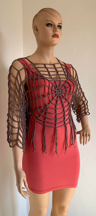 Mannequin mit rotem Etuikleid und gehäkeltem Spinnennetz-Bolero mit Fransen
