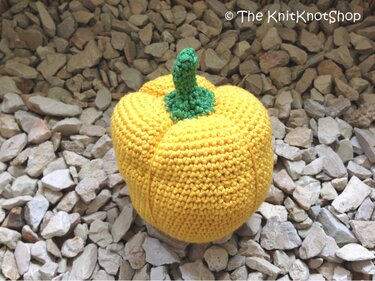 Nahaufnahme einer gehäkelten gelben Paprika mit grünem Stiel
