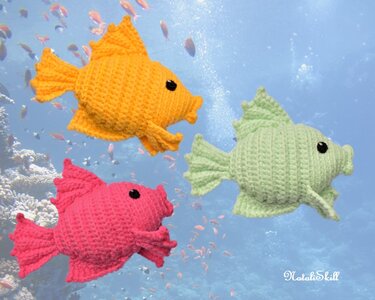 Three crocheted amigurumi fish in orange, pink, and light green against an underwater background