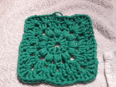 Grünes Granny Square mit voluminösen Puffstichen auf hellem Untergrund