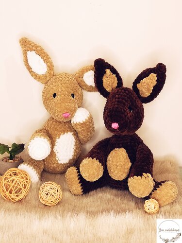 Zwei kuschelige Amigurumi-Osterhasen aus samtigem Garn in Beige und Dunkelbraun, dekorativ arrangiert