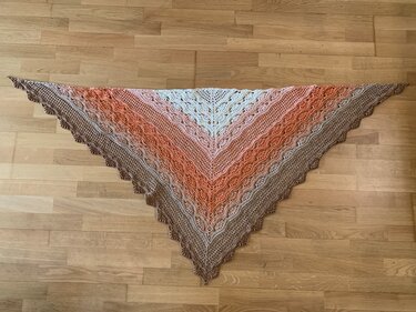 Triangle crochet shawl laid flat, cream to brown gradient with lace panels and scalloped edge