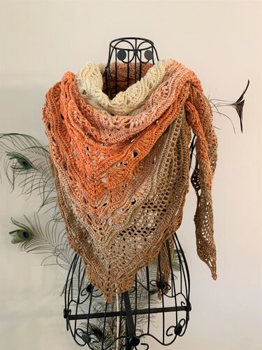 Triangle crochet shawl with an ombre gradient from cream to orange to brown on a wire dress form.
