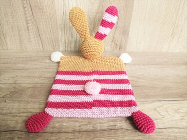 gehäkeltes Schmusetuch in rosa und pink gestreift mit gelbem Hasenkopf und Bommel