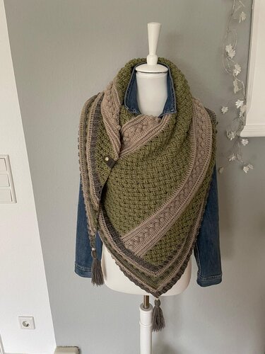 Gehäkeltes Dreieckstuch in Olivgrün, Taupe und Grau auf Schneiderpuppe, mit verschiedenen Mustern und Quasten.