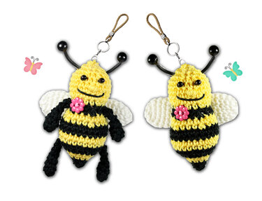 Zwei gehäkelte Bienen‑Schlüsselanhänger in Gelb und Schwarz mit weißen Flügeln, Antennen und rosa Blüte an Schlüsselringen.