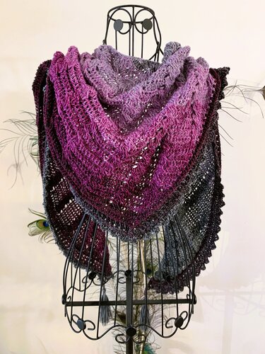 Purple-to-gray crocheted triangle shawl on a wire mannequin, with textured stitches and scalloped edge.