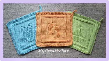 Drei gestrickte Tücher in Blau, Orange und Grün mit Storch-, Babyfuß- und Segelbootmotiv