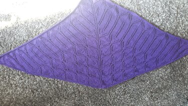 Violettes gestricktes Dreieckstuch mit Ajour-Blattmuster und Mittelreihe auf grauem Teppich