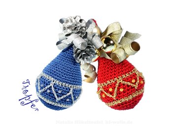 Nahaufnahme von zwei gehäkelten Weihnachtskugeln in Blau und Rot mit Perlen, dekorativen Borten, Schleife und Zapfen
