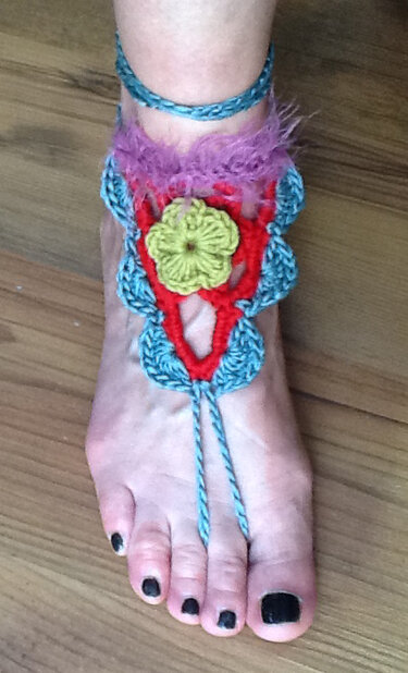 Fuß mit gehäkeltem, buntem Fußschmuck und gelber Blüte