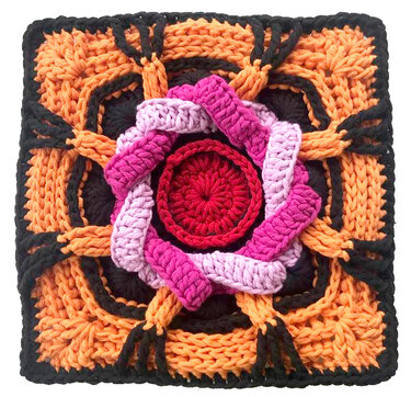 Gehäkeltes Quadrat mit rotem Zentrum, pinken Zöpfen und orange‑schwarzem geflochtenem Rand