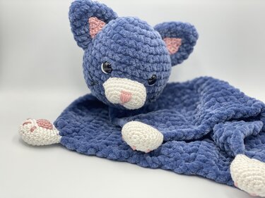 Blue crocheted cat snuggle blanket with attached head and paw corners on white background