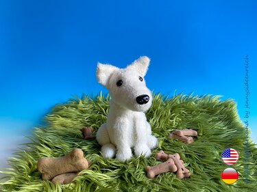 sitzender weißer Amigurumi-Hund mit spitzen Ohren und schwarzer Nase auf grünem Teppich