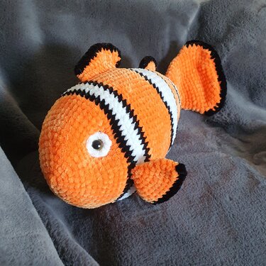 Gestreifter, gehäkelter Clownfisch in Orange, Weiß und Schwarz mit runden Augen.
