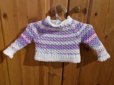 Gestrickter Baby-Pullover in Weiß mit lila-rosa Verlauf und Strukturmuster