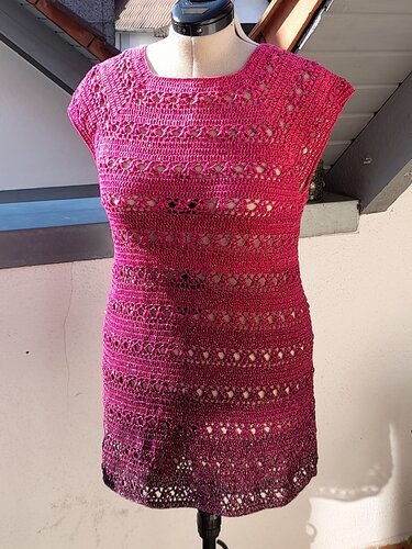 Frontansicht eines sommerlichen, ärmellosen Häkelkleids in Pink mit Ajourmuster und dunklerem Saum
