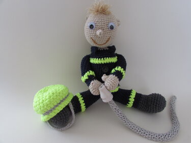 Gehäkelte Feuerwehrmann-Amigurumi-Puppe mit Helm und Schlauch auf weißem Hintergrund