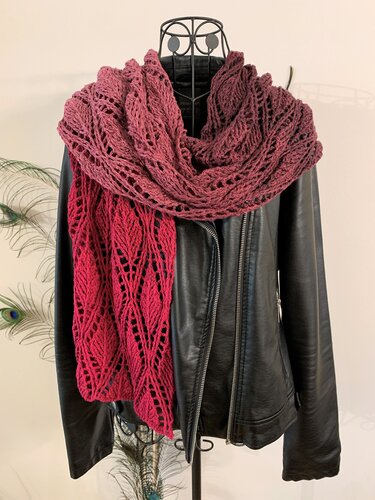 Wine-to-red ombré crocheted lace scarf with leaf motifs draped over a black leather jacket on a dress form