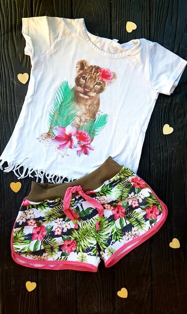 Weißes Kinder-T-Shirt mit Löwenbaby-Motiv und bunte Shorts mit tropischem Blumenmuster
