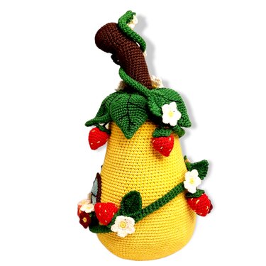 Yellow crocheted gourd-shaped doorstopper decorated with red strawberries, green leaves and white flowers on a white background.