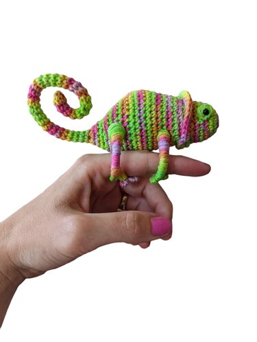 Buntes gehäkeltes Amigurumi-Chamäleon auf einem Finger