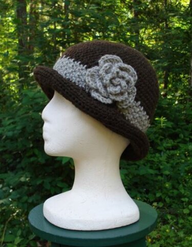 Brown crocheted cloche hat with gray band and flower on mannequin head