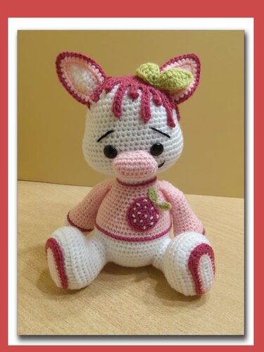Weiß-rosa Amigurumi-Schweinchen mit Erdbeer-Applikation und grünen Blättern auf dem Kopf, gehäkelt