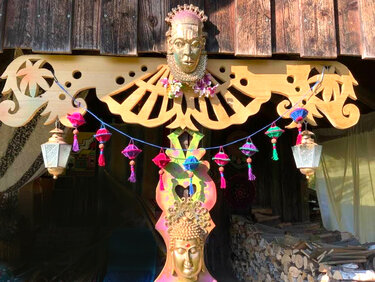 Reihe kleiner gehäkelter Lampions mit Quasten und Perlen an blauer Schnur vor Holzverzierung