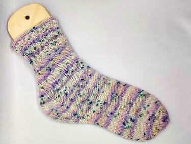 Socke auf Holzsockenformer mit Ajourbündchen und gesprenkeltem Garn