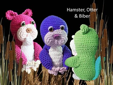 Drei gehäkelte Amigurumi-Tiere (Hamster, Otter, Biber) in Pink, Lila und Grün vor dunklem Hintergrund zwischen Schilfhalmen.
