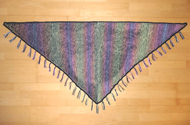 Gestricktes Dreieckstuch mit pastellfarbenen Streifen und Fransen auf Holzfußboden