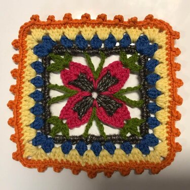 Quadratisches Häkelmotiv mit pinker Blume, grünen Stielen und gelb-blau-orangem Rand