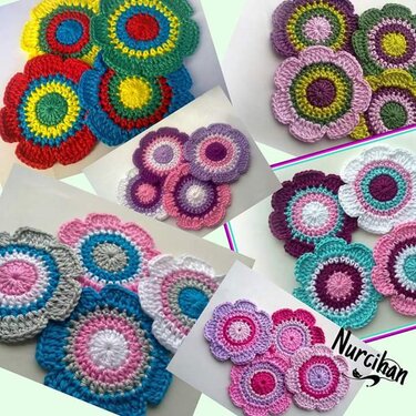 Mehrere gehäkelte, bunte Blumen-Applikationen in verschiedenen Farbkombinationen