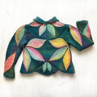 Children's teal garter-stitch jacket with overlapping multicolored leaf-shaped panels, long sleeves and small collar