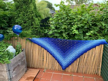 Blaues Dreieckstuch mit Loch- und Wellenmuster auf Bambusmatte, Detailansicht des Maschenbilds