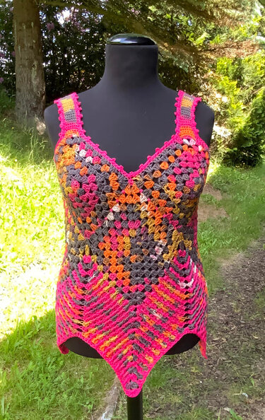 Gehäkeltes buntes Damen-Top auf einer Schaufensterpuppe im Freien mit Granny-Square-Muster und V-Ausschnitt.