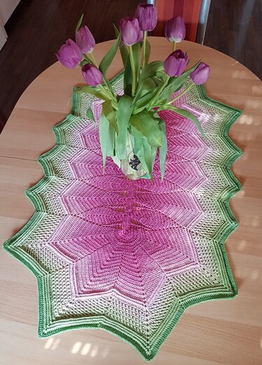 Gehäkelter Sternläufer in Pink und Grün mit Tulpen auf Holztisch
