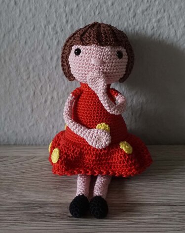 Gehäkelte Amigurumi-Puppe mit Rüssel, rotem Kleid, braunem Haar und schwarzen Schuhen