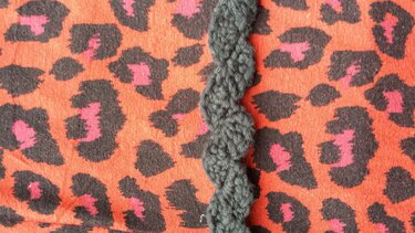 Dunkelgraue, schnell gehäkelte Wellenborte auf orangefarbenem Leopardenstoff