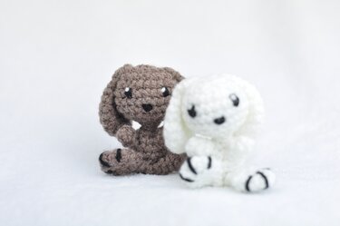 Zwei Amigurumi‑Hasen mit langen Ohren und kontrastierten Pfoten, Nahaufnahme
