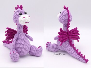 Gehäkelter sitzender Amigurumi-Drache in Lila mit magentafarbenen Flügeln vor hellem Hintergrund