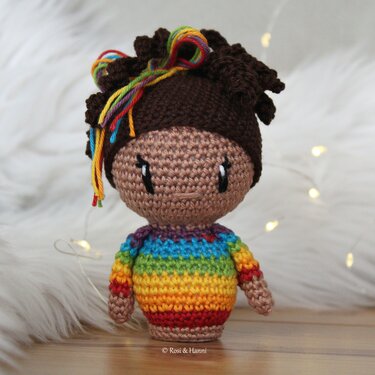 Gehäkelte Amigurumi-Puppe mit braunem Haar, bunten Haarsträhnen und gestreiftem Regenbogenpullover