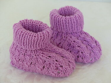 Paar fliederfarbener gestrickter Babyschuhe mit Umschlagbündchen und Ajourmuster