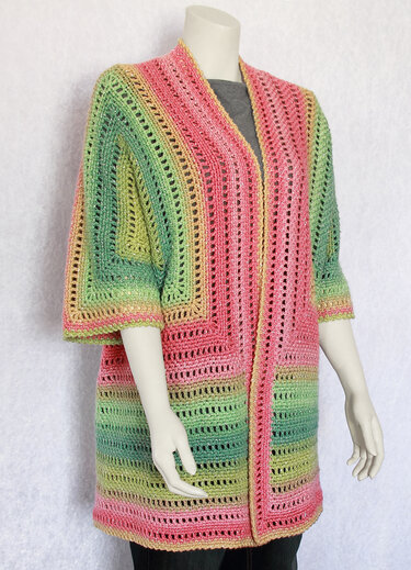 Frontansicht einer gehäkelten Jacke mit Farbverlauf, Lochreihen und 3/4-Ärmeln auf einem Mannequin