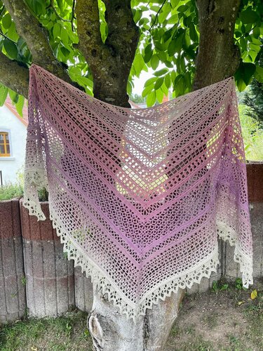 Handgehäkeltes Dreieckstuch in Lila, Rosa und Creme mit sanftem Farbverlauf und filigranem Lochmuster, an einem Baum drapiert
