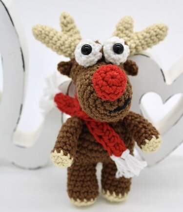 Gehäkeltes braunes Rentier-Amigurumi mit roter Nase und rotem Schal