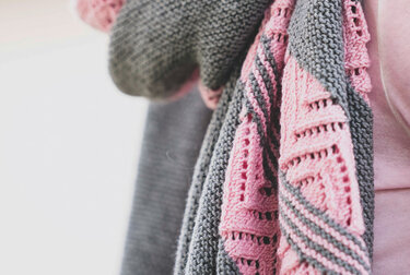 Gestricktes Rechtecktuch in Grau und Rosa, Detailaufnahme mit glatten Flächen und Lochmustern