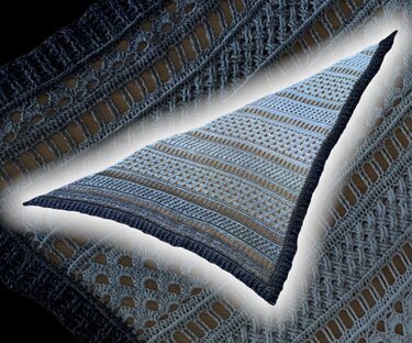 Close-up of crocheted triangle shawl showing eyelet motifs, mesh rows, and dark border